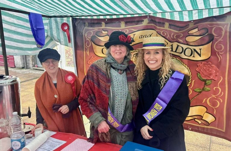 Katie White with Labour party members staffing the Labour stall in Victorian costume; Katie is wearing a votes for women sash