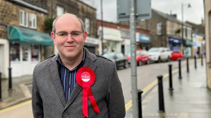 Ian McCargo with red Labour rosette on Yeadon High Street
